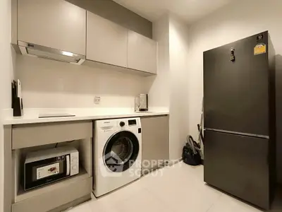 Modern kitchen with sleek appliances including washing machine and fridge