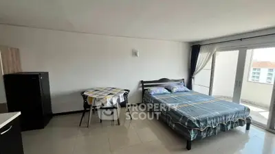 Spacious studio apartment with bed, dining area, and balcony access.