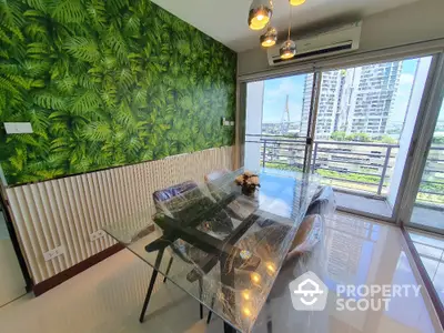 Modern dining area with glass table and lush green accent wall overlooking cityscape