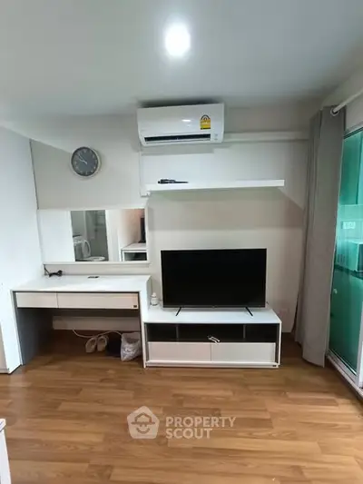 Modern living room with wooden flooring, TV unit, and air conditioning.