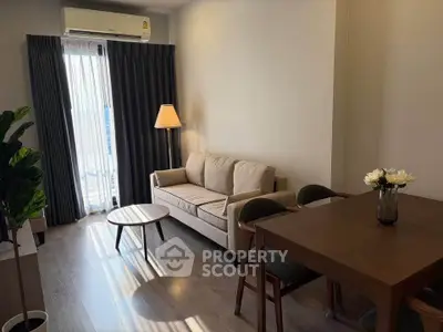 Cozy living room with modern decor, featuring a comfortable sofa, dining table, and natural light from large windows.