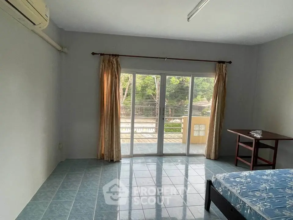 Spacious bedroom with large windows and balcony access, offering serene views and natural light.