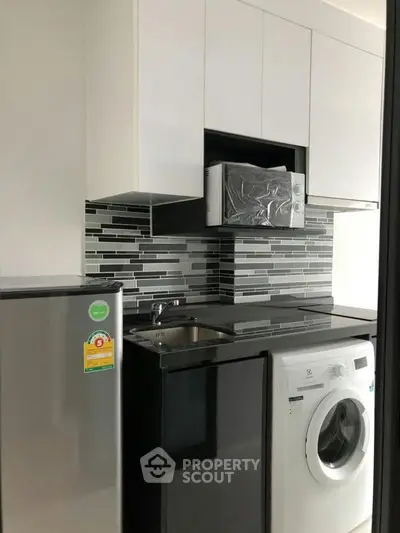 Modern kitchen with sleek appliances and stylish backsplash in compact layout.