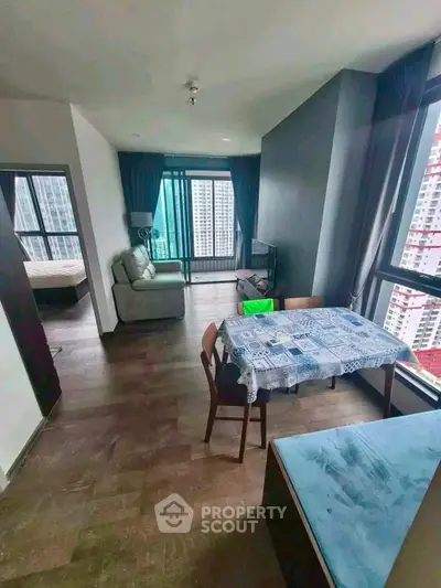 Spacious modern living room with dining area and large windows offering city views.