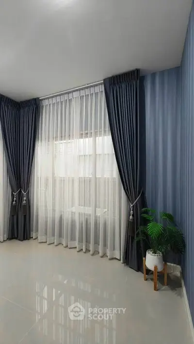 Elegant living room corner with floor-to-ceiling curtains and potted plant