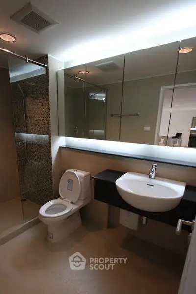 Modern bathroom with sleek fixtures and large mirror in contemporary apartment.