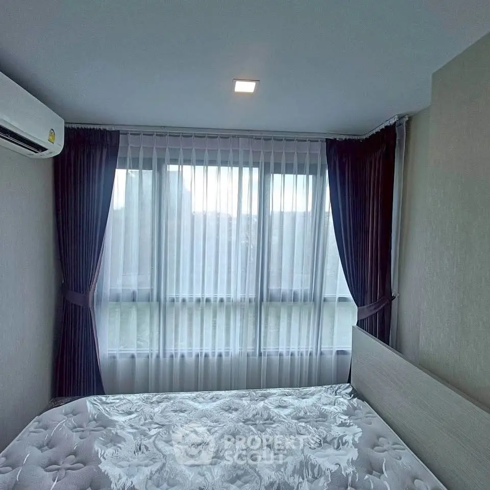 Cozy bedroom with large windows and elegant curtains, featuring a comfortable bed and modern air conditioning.