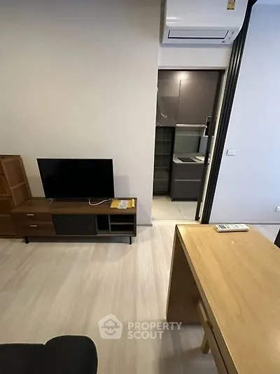 Modern living room with sleek furniture and open kitchen view, featuring air conditioning.