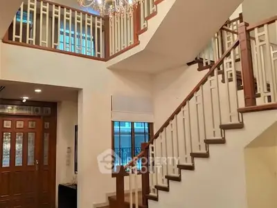 Elegant two-story home interior with chandelier and wooden staircase