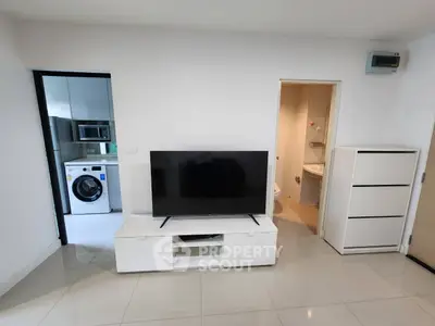 Modern apartment interior with TV, washing machine, and bathroom view.