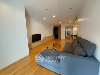Spacious modern living room with wooden flooring and stylish gray sofa in a contemporary apartment.