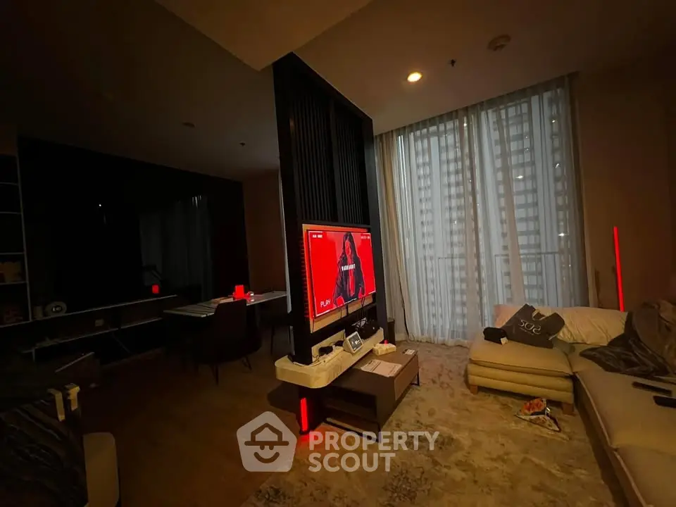 Modern living room with cozy sectional sofa and large TV, featuring floor-to-ceiling windows and ambient lighting.