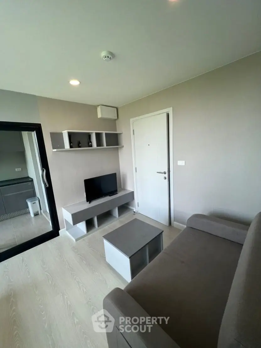 Modern living room with sleek furniture and neutral tones, featuring a compact TV unit and cozy sofa.