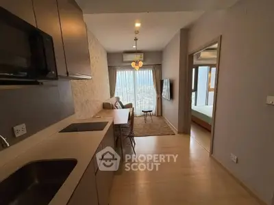 Modern apartment interior with open kitchen and cozy living area, featuring a scenic view from the window.
