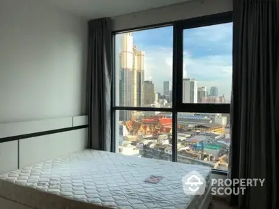 Modern bedroom with city view, large window, and natural light in urban apartment.