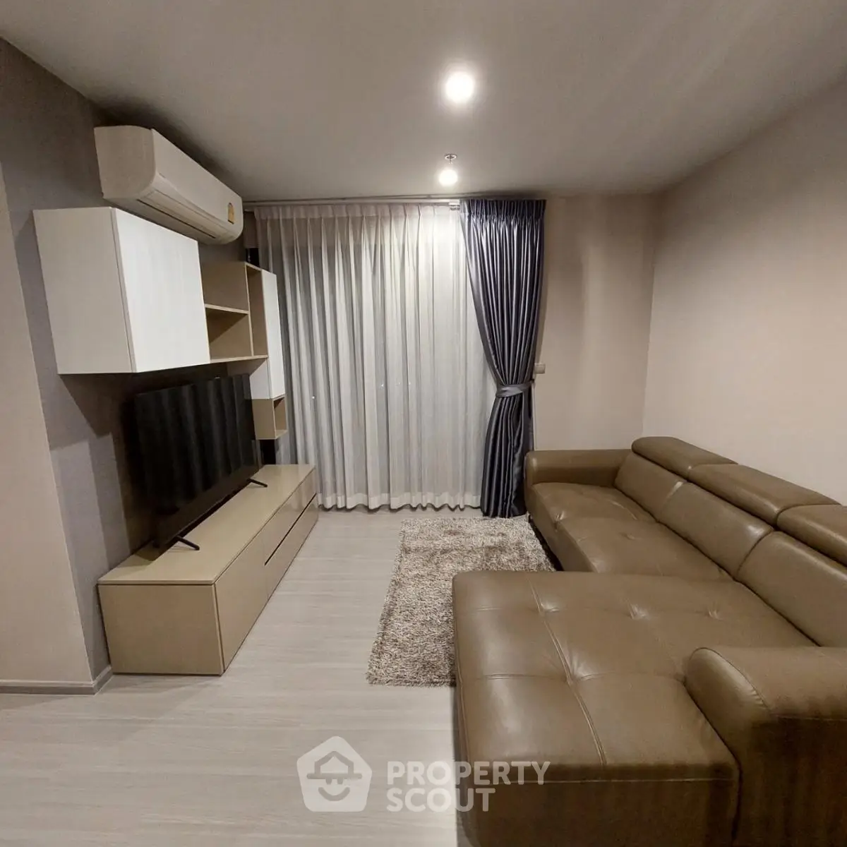 Modern living room with sleek leather sofa and wall-mounted TV, featuring elegant curtains and ambient lighting.
