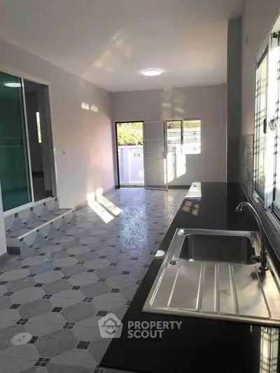 Spacious kitchen with sleek countertops and ample natural light, perfect for modern living.