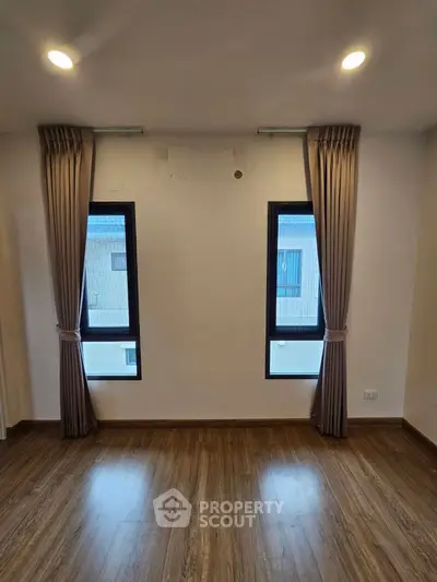 Spacious room with elegant curtains and wooden flooring, perfect for modern living.