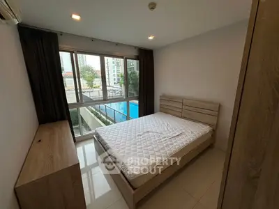 Modern bedroom with pool view, featuring large windows and minimalist wooden furniture.