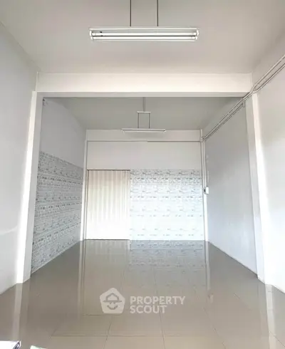 Spacious empty room with tiled floor and modern lighting, ideal for customization.