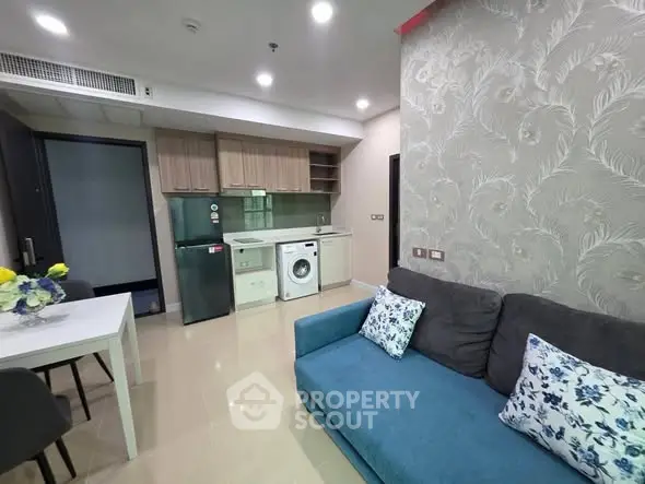 Modern living room with open kitchen, featuring washing machine and stylish decor.