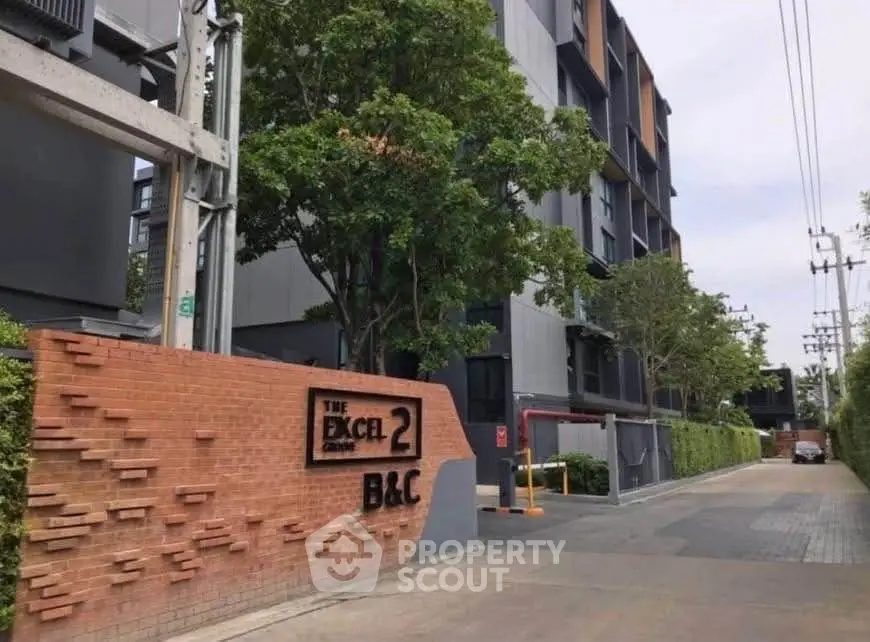 Modern residential building exterior with lush greenery and brick entrance signage.