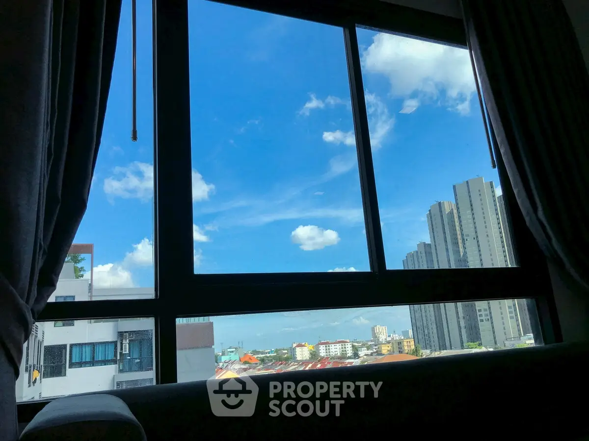 Stunning cityscape view from a modern apartment window with clear blue skies.