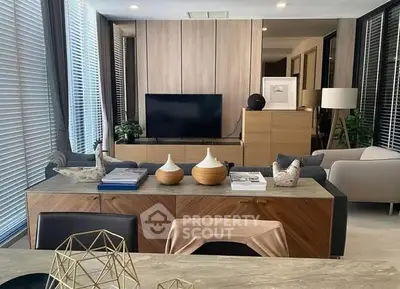 Modern living room with stylish decor and large TV, featuring elegant furniture and natural light.