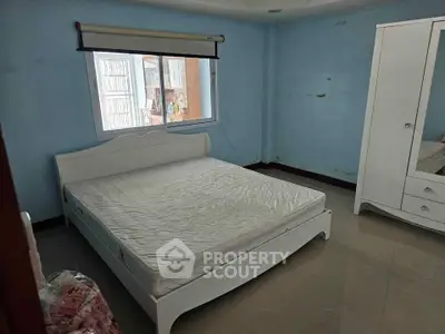 Spacious bedroom with large window and modern white furniture, perfect for a cozy and comfortable living space.