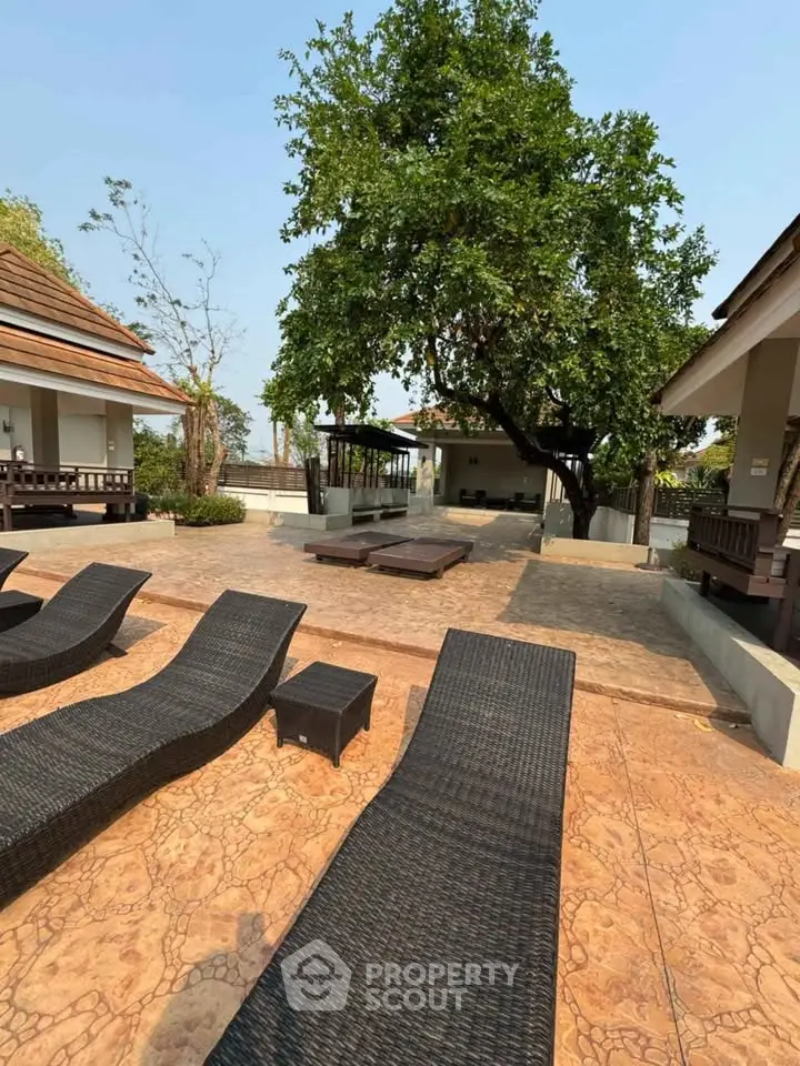 Spacious outdoor patio with stylish loungers and lush greenery, perfect for relaxation and entertaining.
