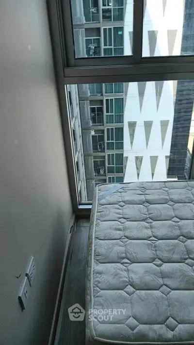 Modern bedroom with large window offering urban city view and natural light.