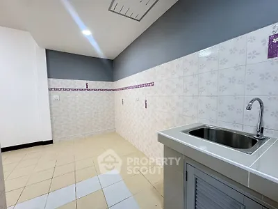 Spacious kitchen area with tiled walls and modern sink, ideal for culinary enthusiasts.