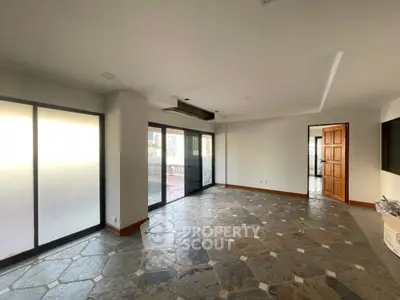 Spacious living room with stone flooring and large windows offering natural light.