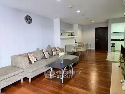 Spacious living room with modern decor and hardwood floors in a stylish apartment.