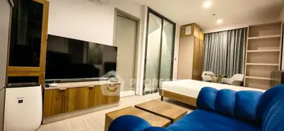 Modern living room with blue sofa and large TV in stylish apartment