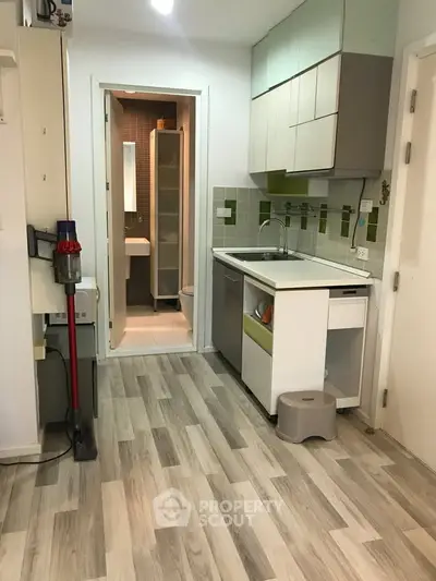 Compact kitchen with modern cabinetry and green tile accents