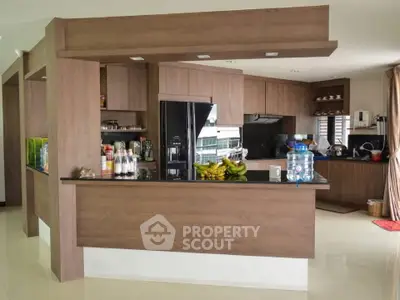Modern kitchen with sleek wooden cabinetry and black countertops, featuring a spacious open layout and contemporary appliances.