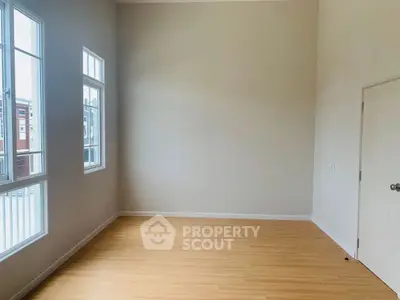 Spacious empty room with large windows and wooden flooring, perfect for customization.
