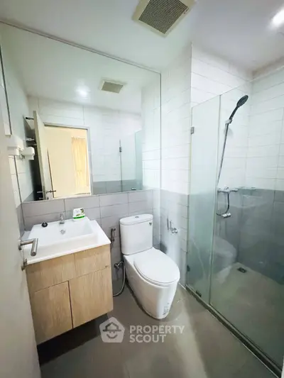 Modern bathroom with glass shower and sleek vanity in contemporary apartment.