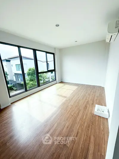 Spacious empty room with large windows and wooden flooring, perfect for customization.