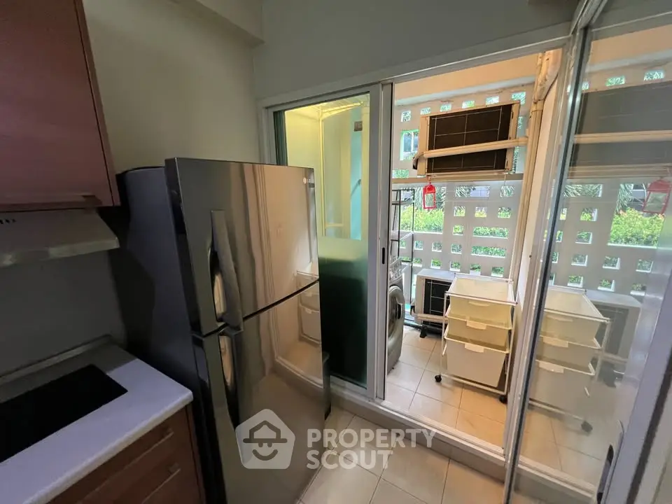 Modern kitchen with stainless steel fridge and sliding glass doors leading to a utility area.