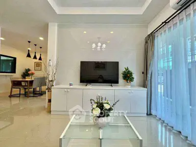 Modern living room with sleek TV unit and elegant decor, featuring open layout and natural light.