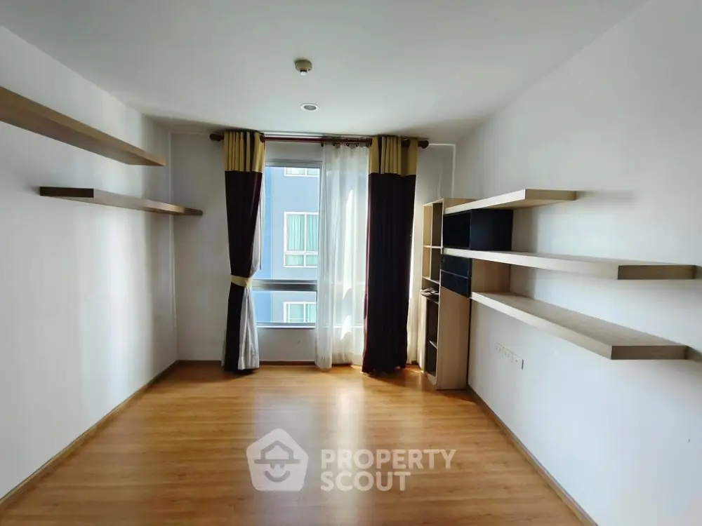 Spacious modern living room with wooden flooring and large window view.