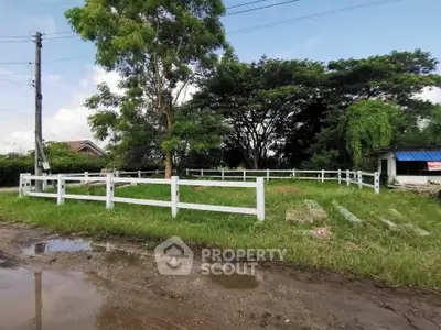 Charming vacant lot with lush greenery and white fence, perfect for building your dream home.