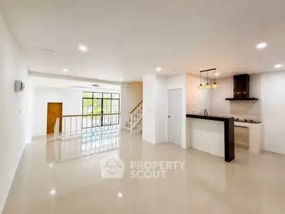 Spacious open-plan living area with modern kitchen and large windows.