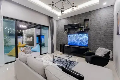 Modern living room with stylish decor and large TV, opening to a cozy outdoor patio with bean bags.