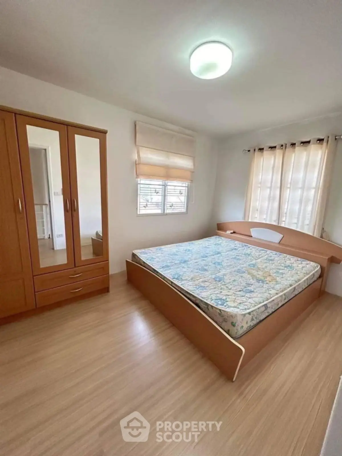 Spacious bedroom with wooden flooring and ample natural light