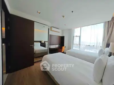 Spacious modern bedroom with twin beds and large window offering natural light.