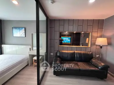 Modern studio apartment with sleek design, featuring a cozy living area and a comfortable bedroom separated by glass partition.