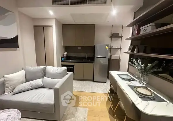 Modern compact living room with kitchen and dining area, featuring sleek furniture and appliances.